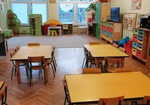Sala przedszkolna. Żółte stoliki dziecięce, zabawki