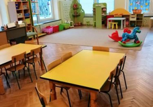 Sala przedszkolna. Żółte stoliki dziecięce, zabawki