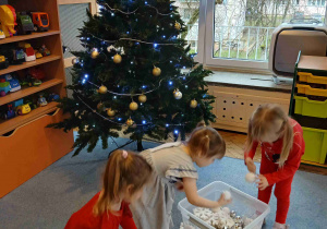Dzieci ubierają choinkę w swojej sali.