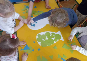 Dzieci pracując zespołowo, klasyfikują figury geometryczne.