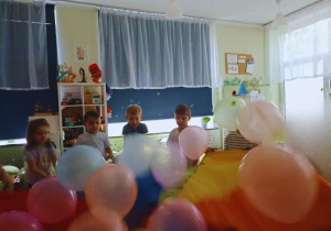 Dzieci bawią się z chustą animacyjną i balonami.