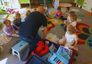 Dzieci przyglądają się grającemu przedmiotowi, który Pan Jacek wyjął swojej magicznej walizki.