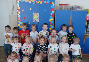 Dzieci pozują do zdjęcia na tle wielu kropek.