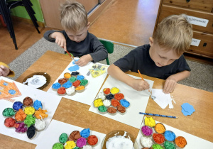 Chłopcy naklejają elementy na kartkę.