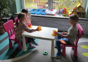 Dzieci bawią się przy stoliczkach klockami.