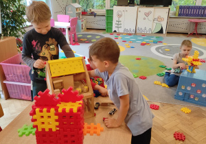 Chłopcy bawią się w domku dla lalek.