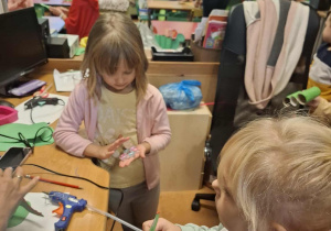 Dziewczynki czekają w kolejce do przyklejenia elementów na klej na gorąco.
