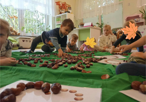 Dzieci układają kształt figur z darów jesieni.