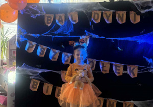 Dziewczynka pozuje do zdjęcia przy upiornej dekoracji.