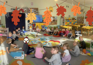 Dzieci siedzą w kole i biorą udział w zajęciach.